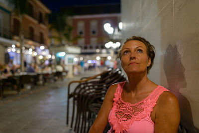Portrait of woman standing against illuminated city