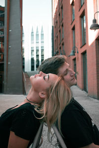 Side view of couple sitting against buildings