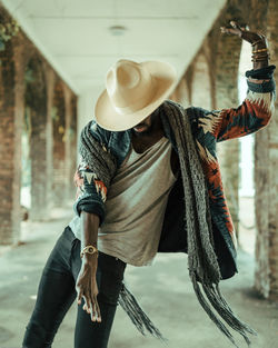 Midsection of man wearing hat standing against wall in city