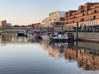 Boats moored at harbor in city against clear sky
