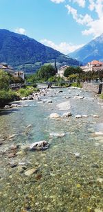 Scenic view of river by mountains against sky