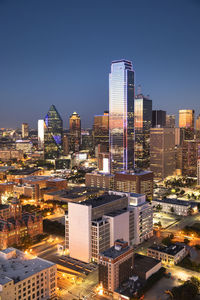 Illuminated buildings in city against clear sky