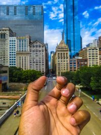 Close-up of man holding hand against buildings in city