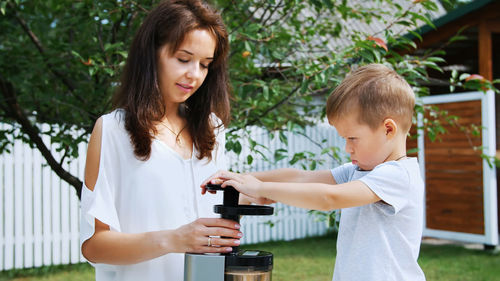 Summer, in the garden. mother and four-year-old son make fresh juice of mandarins, put mandarin