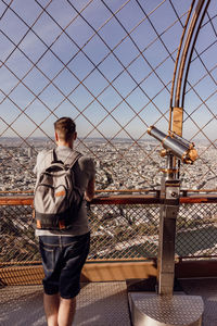 Full length of man standing on railing against sky