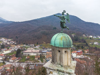 Statue amidst buildings in city against sky