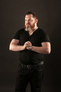 Portrait of young man standing against black background