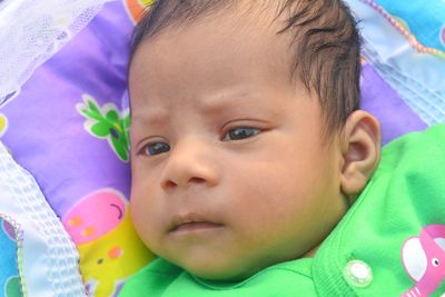 Close-up portrait of cute baby lying on bed