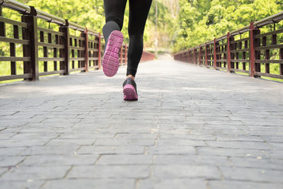 Low section of woman running on footbridge