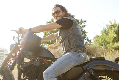 Smiling man wearing sunglasses sitting on bike