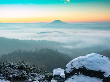 Scenic view of snow covered mountains against sky during sunset