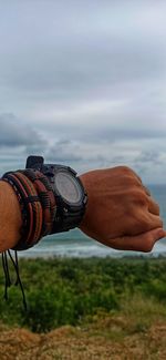 Close-up of hand against sea and sky