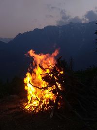 Bonfire against mountain range at night