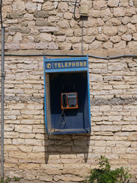 Telephone booth mounted on wall during sunny day