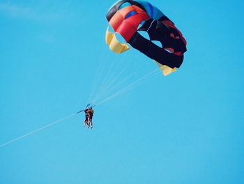 Low angle view of parachuting against clear blue sky