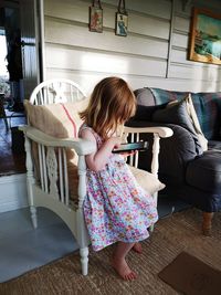 Girl using mobile phone while sitting on chair at home