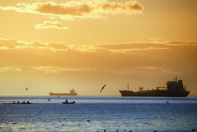 Silhouette boats in sea against sky during sunset