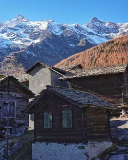 Houses by snowcapped mountains against sky