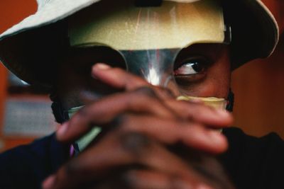 Close-up of man wearing mask with hands clasped