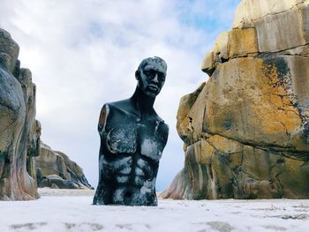Statue on rock against sky during winter