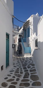 Alley amidst buildings in town against blue sky