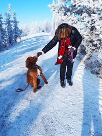 Woman with dog on snow during winter