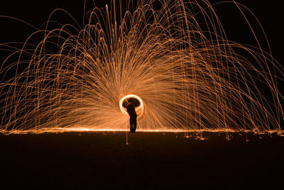 Full length of silhouette man spinning wire wool at night