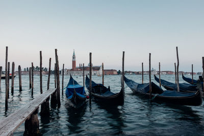 Gondolas moored on sea against clear sky