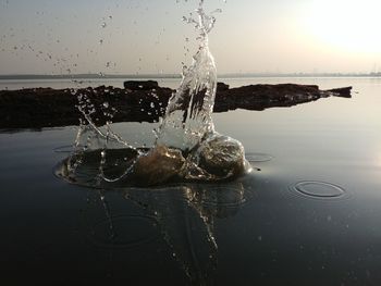 Close-up of water splashing on sea against sky