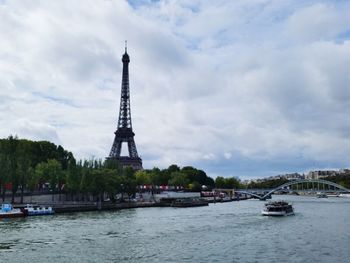 Tower in city against cloudy sky
