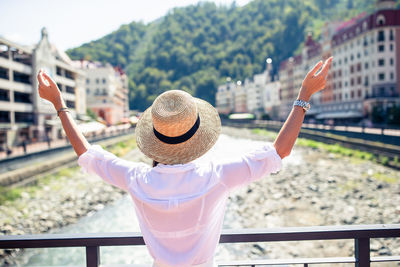 Rear view of woman with arms outstretched standing outdoors