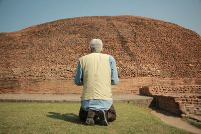 Rear view of man kneeling on grass