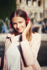 Portrait of smiling woman listening music in city