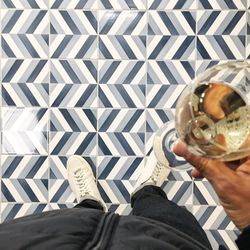 Low section of man holding champagne over patterned floor