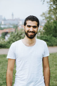 Portrait of smiling young man standing on grassy field