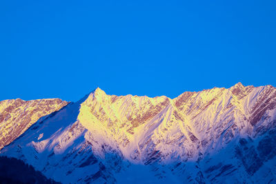 Scenic view of snowcapped mountains against clear blue sky