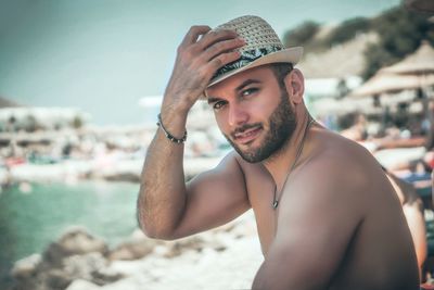 Portrait of handsome man wearing hat at beach