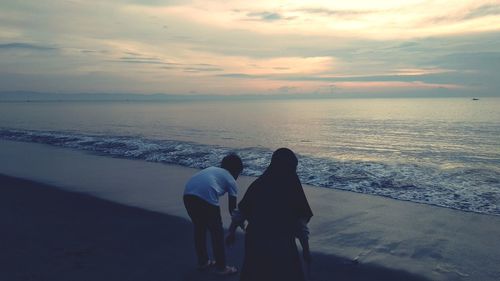 Women on beach against sky during sunset