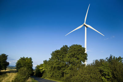 Low angle view of windmill against clear blue sky