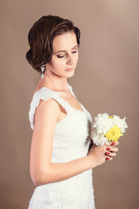 Portrait of woman standing against white wall