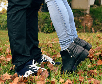 Low section of couple standing on grassy field