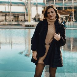 Portrait of young woman standing against fountain 