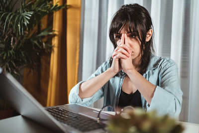 Frustrated young woman by laptop in office