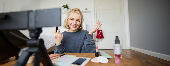 Portrait of young woman using mobile phone while sitting at home