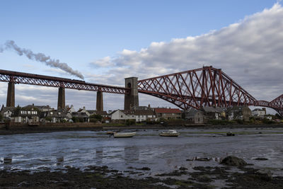 Bridge over river in city against sky