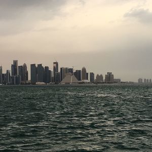 City skyline by sea against sky