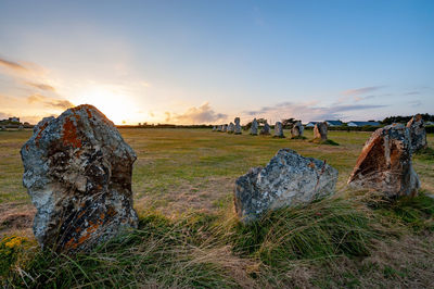Panoramic shot of rocks on field against sky during sunset