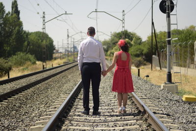 Rear view of people walking on railroad track