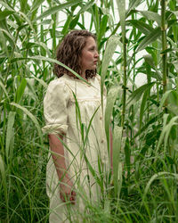 Woman looking away from camera while standing in field