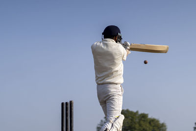 A cricketer playing cricket on the pitch in white dress for test matches.sportsperson hitting a shot